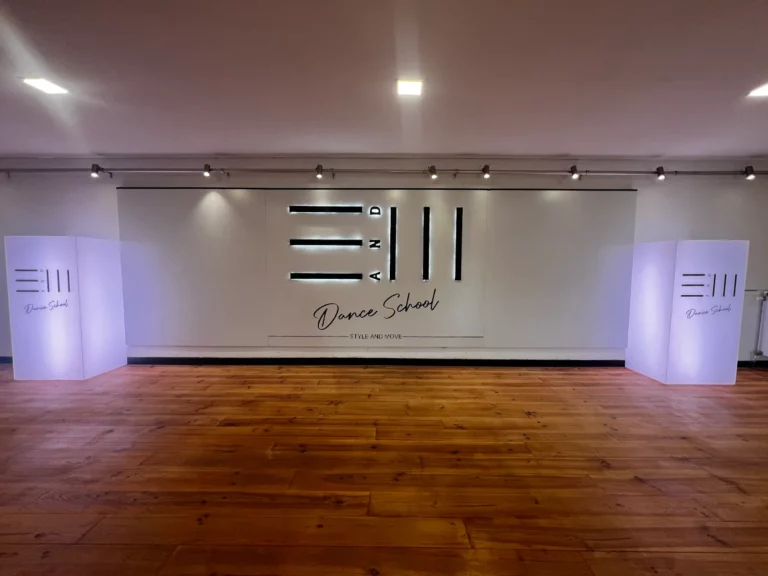Le Studio 1 de Style and Move : parquet et mur blanc avec le logo lumineux, à Marchienne-au-Pont